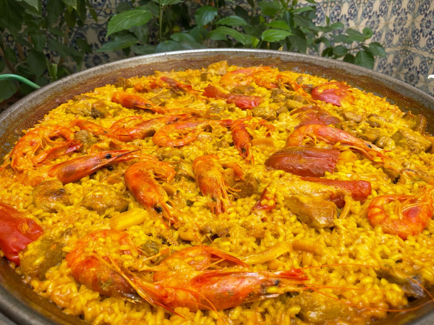 In the photo you can see a seafood paella almost cooked. The rice has an intense yellow color and you can see shrimp and tuna on it.