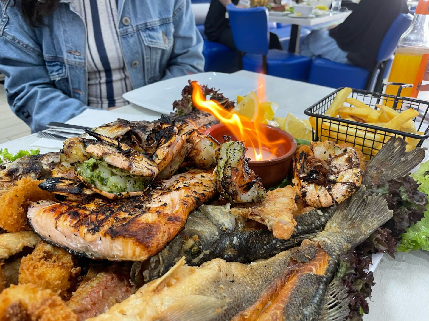 In the photo you can see a plate with a variety of grilled fish and a small pot with salt on fire. It was taken in a restaurant in the Neukölln neighborhood in Berlin.
